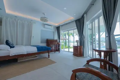 a bedroom with a bed and sliding glass doors at Coco Golf Villa in Ban Huai Luk (1)