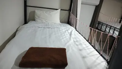 a bed with white sheets and a brown blanket at Bambus Restaurant, Bar & Hostel in Patong Beach