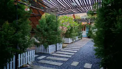 a garden with a white fence and trees at Bambus Restaurant, Bar & Hostel in Patong Beach