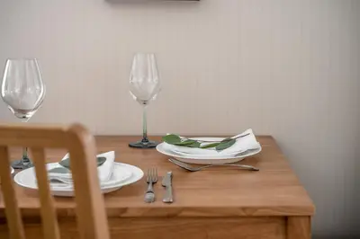 a wooden table with two glasses and a plate and fork at Title V Palm View 4fl Pool Gym Hammam in Rawai Beach