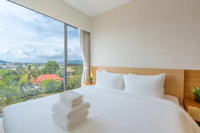 a bedroom with a white bed with a large window at Laguna Lakeside apartments with panoramic view in Bang Tao Beach