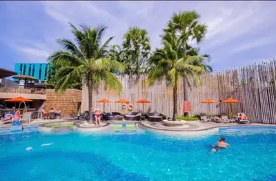a large swimming pool with palm trees and people in it at Kata Beach Guesthouse-The Beach Condo in Kata Beach