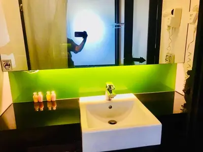 a person taking a picture of a sink in a bathroom at Kata Beach Guesthouse-The Beach Condo in Kata Beach