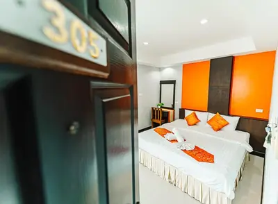 a bedroom with two beds with orange and white pillows at Saiyuan Residence Phuket in Rawai Beach