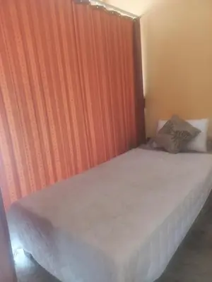 a bed in a room with an orange wall at Salika Hostel Patong Phuket in Patong Beach