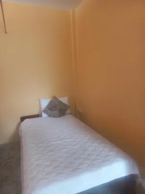 a small bedroom with a white bed with a pillow at Salika Hostel Patong Phuket in Patong Beach