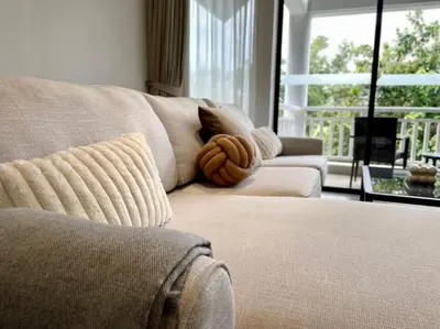 a couch with a pillow on it in a living room at Allamanda Laguna Phuket 2 bedroom apartment Bang Tao Beach in Laguna Phuket