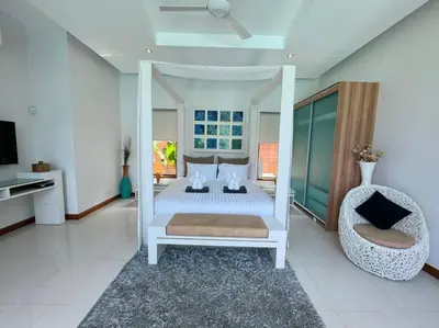 a white bedroom with a bed and a chair at Aromdee 2 Villa by G Estate Phuket in Ban Saiyuan (1)