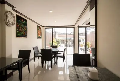 a dining room with a table and chairs and a clock at Paripas Express Patong in Patong Beach