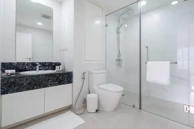 a white bathroom with a toilet and a glass shower at 1 Bedroom Brandnew Apartment in Patong Tower t in Patong Beach