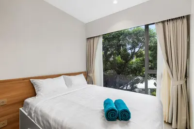 two blue slippers sitting on a bed in front of a window at Laguna Lakeside BangTao by My Home Phuket in Bang Tao Beach
