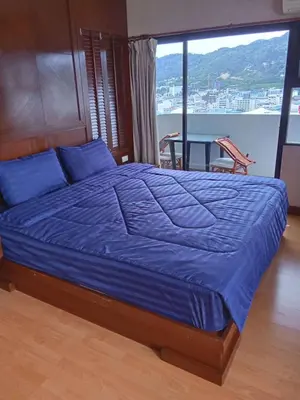 a bed with blue pillows in a room with a window at Apartment in Patong Tower in Patong Beach