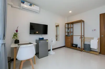 a white room with a desk and a tv on the wall at Wow Academy & Stay Soi Tai-Aed 2A in Ban Suan