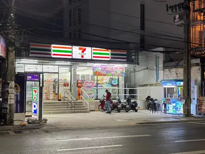 a man standing outside of a gas station at night at patong v hotel in Patong Beach