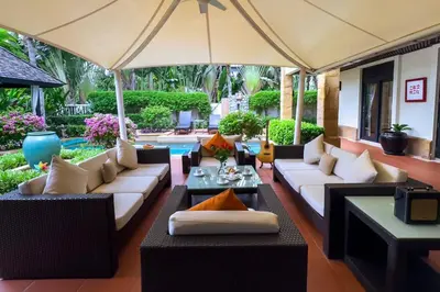 an outdoor living room with couches and an umbrella at Charming Chom Tawan Villa 3 bdr in Layan Beach