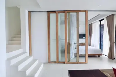 a bedroom with glass doors and a bed and a staircase at Bandara Pool Villas, Phuket in Panwa Beach