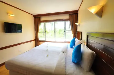 a bedroom with a bed with blue pillows and a window at Isle Beach Resort Krabi-SHA in Klong Muang Beach