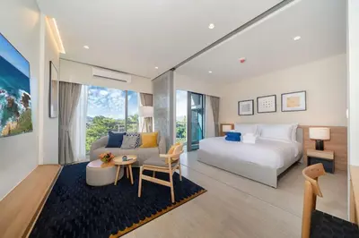 a bedroom with a bed and a couch and a table at New 1 br studio in Laguna Phuket in Phuket Town