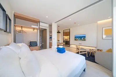a bedroom with a large white bed and a living room at New 1 br studio in Laguna Phuket in Phuket Town