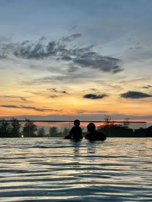 two people sitting in the water at sunset at The Deck condominium Patong beach in Patong Beach