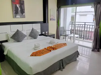 a bedroom with a large white bed and a balcony at The Star House in Patong Beach