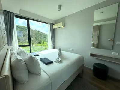 a bedroom with a white bed with a large window at Cozy Surin apartment at 6 Avenue by Lofty in Surin Beach