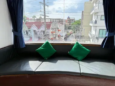 a couch with two green pillows in front of a window at Heaven House Restro & Bar in Patong Beach