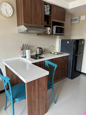 a kitchen with a counter and two blue chairs at Nai Harn Beach Condo (P1) in Rawai Beach