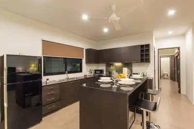 a kitchen with brown cabinets and a black counter top at Tropical 3BR Pool Villa Nga Chang NC10, Gated Residence, 10 min Drive to Nai Harn Beach in Rawai Beach