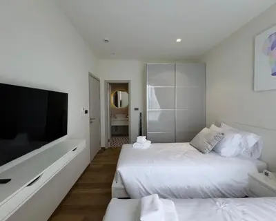 a white bedroom with two beds and a flat screen tv at The Title Halo 1 Apartment 10 min to Nai Yang Beach in Nai Yang Beach