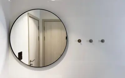 a mirror hanging on a white wall in a bathroom at The Title Halo 1 Apartment 10 min to Nai Yang Beach in Nai Yang Beach