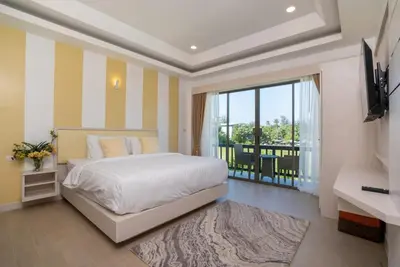 a bedroom with a bed and a television and a balcony at Private Villas Bangtao in Bang Tao Beach