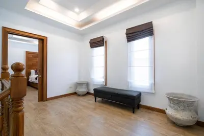 a living room with a black ottoman and two windows at Private Villas Bangtao in Bang Tao Beach