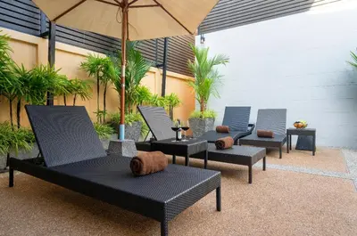 a group of chairs and an umbrella on a patio at Private Villas Bangtao in Bang Tao Beach