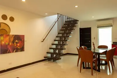 a dining room with a staircase and a table and chairs at 12 minutes Patong Security Gym Sauna AP12 #V28 in Kamala Beach