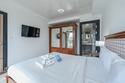 a bedroom with a white bed and a television at Уютные апартаменты NBC Nai Harn in Rawai Beach