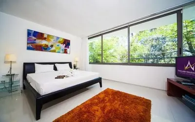 a bedroom with a bed and a tv and some windows at Atika Villas in Patong Beach