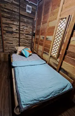 a bed in a room with a wooden wall at Big Hug Home - Sa med kaw in Ban Takhrai