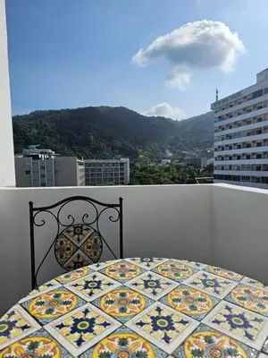 a bed on a balcony with a view of a city at Yuya's sweet Condo suite in Patong Beach
