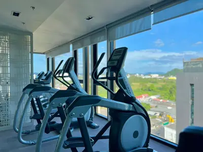 a row of treadmills in a gym with windows at 1BR Apartment with Rooftop Pool - The Base Height Phuket town in Ban Sam Kong