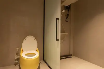 a bathroom with a yellow toilet in a stall at YUSU Hotel \u7fbd\u5bbf\u9152\u5e97 in Phuket Town