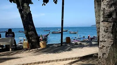 a person sitting on a bench looking at the ocean at By the Sea Apartment Hotel in Krabi town