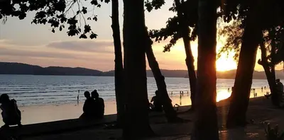 a group of people sitting on the beach watching the sunset at By the Sea Apartment Hotel in Krabi town