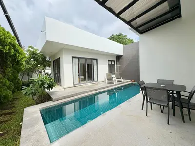 a swimming pool with a table and chairs next to a house at Garden 2 bedrooms pool villa in Laguna Phuket