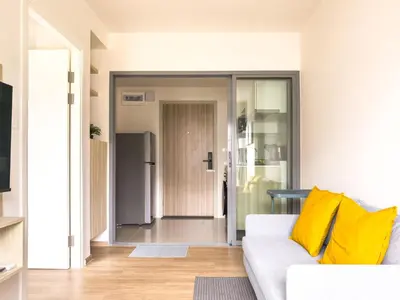 a living room with a white couch and yellow pillows at PHYLL Condo Private Beach Vibes at Central Phuket 1 BR Unique Garden View in Ban Rangeng