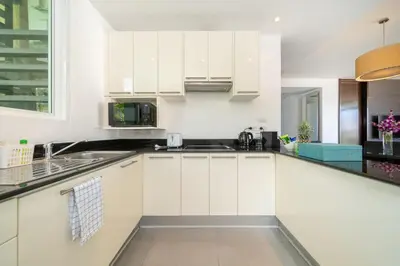 a kitchen with white cabinets and a sink at Karon Beachfront Apartment 724 in Karon Beach