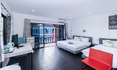 a hotel room with two beds and a red chair at Belle Cose Guest House Phuket in Patong Beach