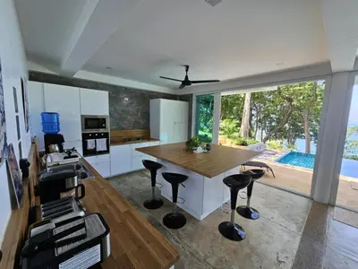 a kitchen with a wooden table and stools at Beachfront villa in Rawai in Phuket Town