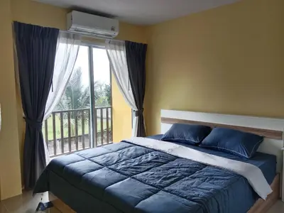 a bedroom with a blue bed and a window at Yellow house in Ban Saiyuan (1)