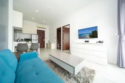 a living room with a blue couch and a kitchen at Spacious Pool View 1BR Apartment in Utopia Naiharn Residence near Beach, UTN D604 in Rawai Beach